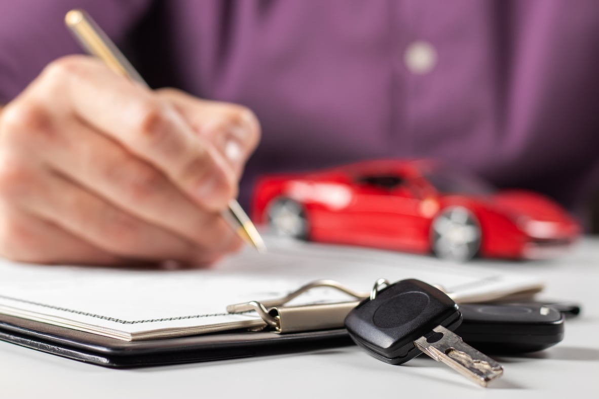 Man signing car insurance document or lease paper. Writing signature on contract or agreement.